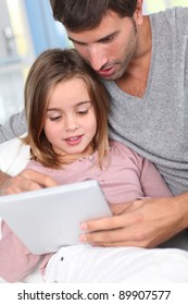 Father And Child Using Electronic Tablet At Home