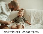 Father, child and wipe nose of sick kid on sofa in home living room, funny and laugh for care. Dad, boy and toddler with tissue for flu, allergies or cold, virus or disease, illness or covid in house