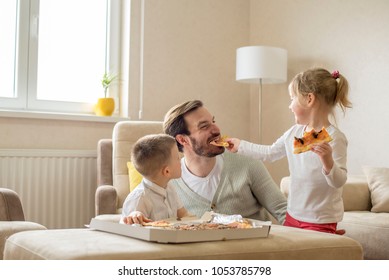 Father with children eating pizza together and having fun in living room - Powered by Shutterstock