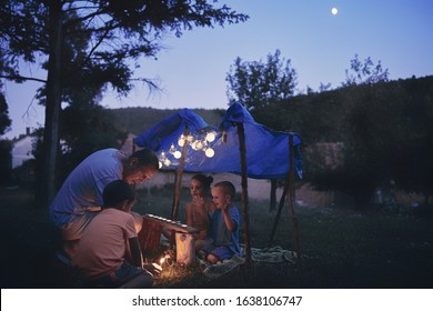 Father With Children Playing Under Their Backyard Tent.