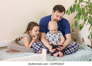 Father With Children Using Digital Tablet Computer Together At Home. Dad With Daughter And Son Watching Cartoons, Play Games Or Have Video Chat. Weekend Family Leisure Using Modern Technology.