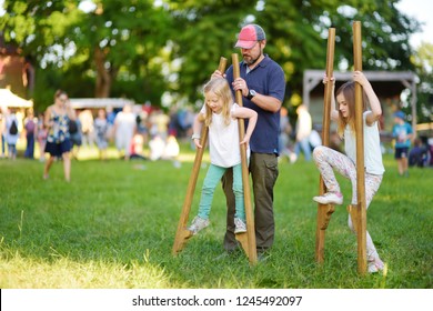 Father And Children Walking On Stilts During Annual Medieval Festival, Held In Trakai Peninsular Castle. Fun Activity For Kids And Parents.