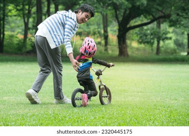 Father or coach supervises the little rider while training at green lawn , with parent supervision, outdoor sports for kids - Powered by Shutterstock