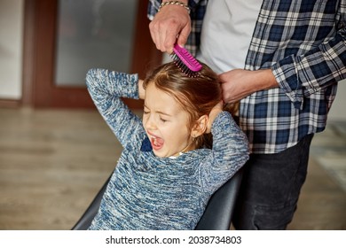 Father Combing, Brushing His Daughter's Hair At Home, Child Making Faces About Hair Pulling, Angry Girl Feeling Pain, Family Moments, Spending Time Together.