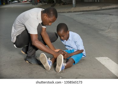 Father Comforting His Son Crying, Child Fallen On The Road Having A Knee Injury