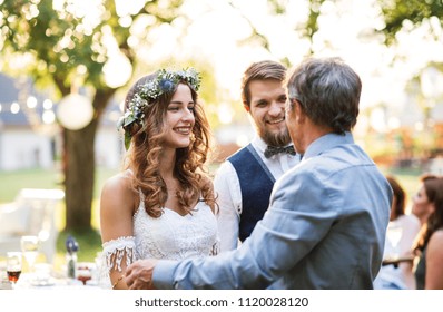 A father congratulating bride and groom at wedding reception in the backyard. - Powered by Shutterstock