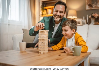 Father with cup of hot drink and son play board, table top game together at home - Powered by Shutterstock