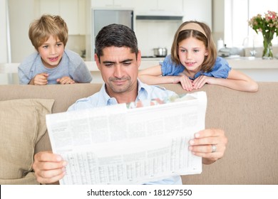 Father And Cute Children Reading Newspaper At Home