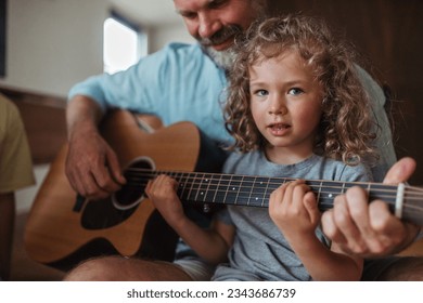 Father and cute daughter playing guitar together. - Powered by Shutterstock