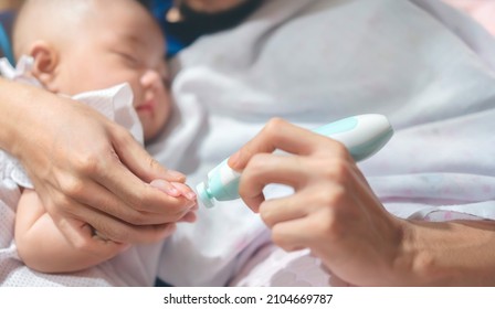 Father Cutting My Baby's Nails With Electic Nail Clipper While Baby Sleep.