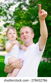 Father Dad Parent Holding Baby Boy Outdoors In Summer Garden Pointing Something In Sky