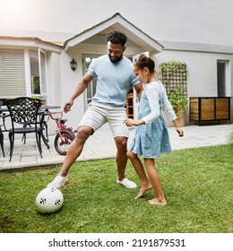 Father And Daughter Bonding, Playing With Soccer Ball In Backyard At Home, Smiling And Having Fun. Happy Parent Being Playful And Enjoying Family Time With His Child. Guy Being Active With His Kid