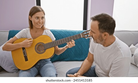 Father and daughter bonding while sitting on the sofa at home, playing classical guitar; their casual expressions radiate love and relaxed enjoyment in the cozy living room. - Powered by Shutterstock