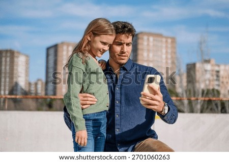 Father and daughter bonding while using a mobile phone to take a selfie
