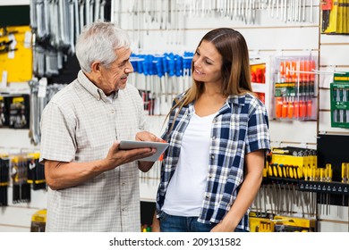 Father And Daughter With Digital Tablet Looking At Each Other In Hardware Shop