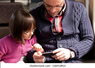 Father And Daughter With Eyeglasses Watching A Video On The Mobile Phone While Traveling In Train