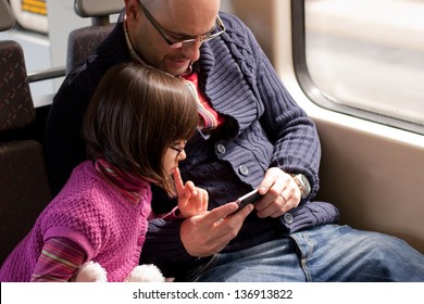 Father And Daughter With Eyeglasses Watching A Video On The Mobile Phone While Traveling In Train