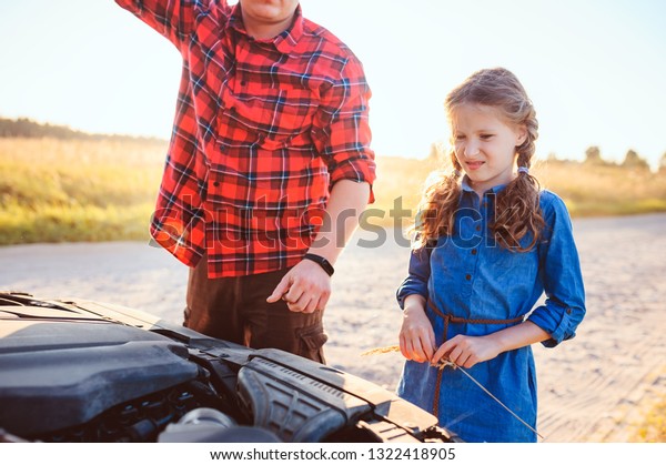 father and daughter fixing problems with car\
during summer road trip. Kid helping\
dad.