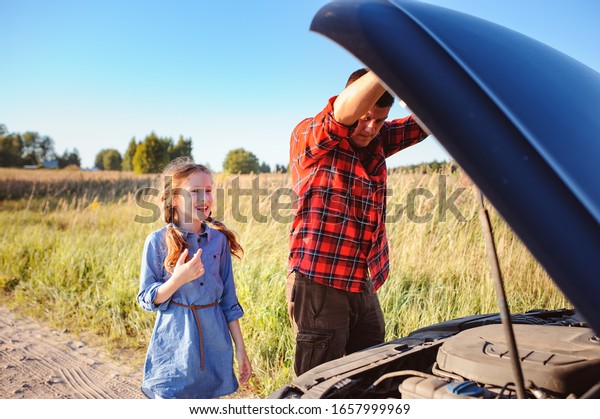father and daughter fixing problems\
with car during summer road trip. Kid girl helping\
dad.