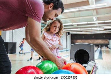 Father and daughter having fun at bowling alley. Choosing a ball color.