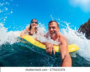 Father and daughter having fun on the beach while floating on airbed