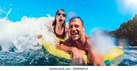 Father and daughter having fun on the beach while floating on airbed - Powered by Shutterstock