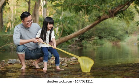 Vater und Tochter, die eine sonnige Aktivität gemeinsam haben. Sie versuchen, Fisch zusammen mit lustiger Bewegung zu fangen.