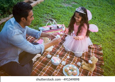 Father and daughter having toy tea party in the garden - Powered by Shutterstock