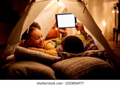 Father And Daughter At Home Lying In Indoor Tent Or Camp Watching Or Streaming To Digital Tablet - Powered by Shutterstock