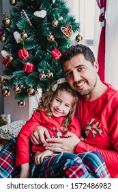 Father And Daughter At Home Wearing Matching Pajamas. Christmas Season