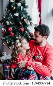 Father And Daughter At Home Wearing Matching Pajamas. Christmas Season