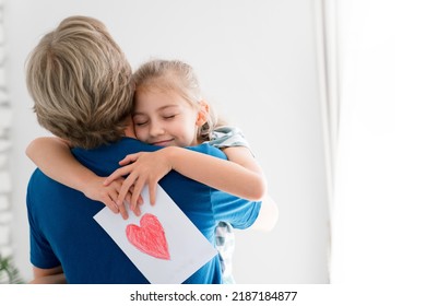 Father And Daughter Hugging At Home. Child Giving Gift And Greeting Parent On Father's Day. Happy Family Cuddles. Togetherness, Tenderness, Love, Empathy In Relationships. Authentic Lifestyle