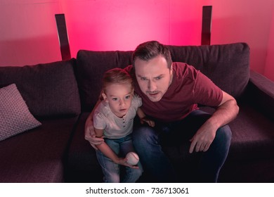 Father And Daughter Hugging And Watching A Baseball Game At Home