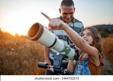 Father and daughter observing the sky with a telescope. - Powered by Shutterstock