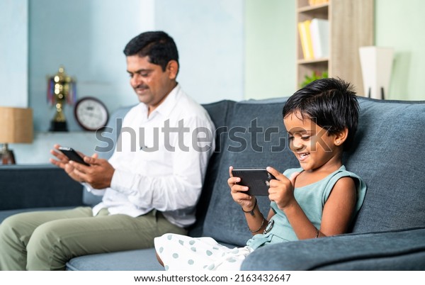 Father and daughter on sofa separately busy
using mobile phone at home - concept of digital divide, social
media and technology
addiction