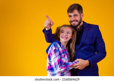 Father And Daughter On Yellow Background With Space For Text. Father Points To The Horizon Showing Something To His Daughter.