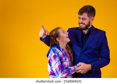 Father And Daughter On Yellow Background With Space For Text. Father Points To The Horizon Showing Something To His Daughter.