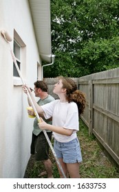 A Father And Daughter Painting The House Togehter.  Vertical View.