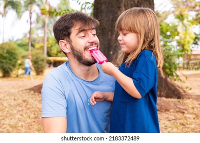 Father and daughter in the park sucking on a delicious popsicle - Powered by Shutterstock