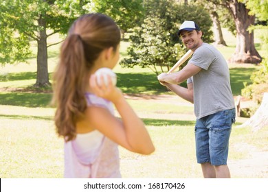 Father And Daughter Playing Baseball In The Park