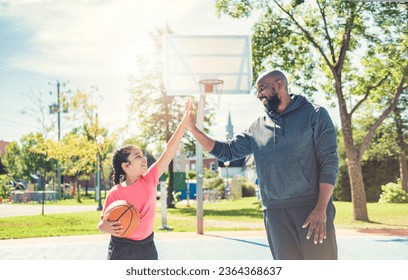 A father and daughter playing basketball in the park - Powered by Shutterstock