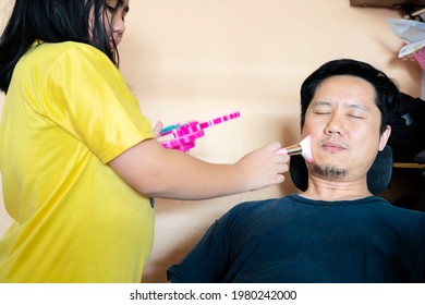 father and daughter playing at home with make up brush. Girl dressed up in a fairy costume applying make-up on fathers face at home - Powered by Shutterstock