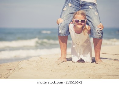 Father and daughter  playing on the beach at the day time. Concept of friendly family.