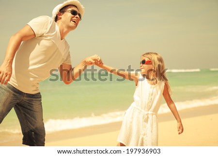 father and daughter playing on the beach at the day time