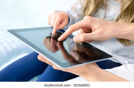 Father with daughter playing on digital tablet. Selective focus on the child's finger. - Powered by Shutterstock