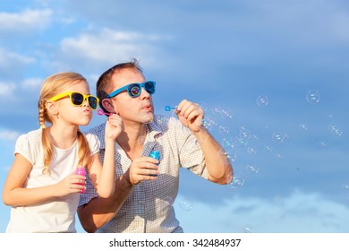 Father And Daughter Playing In The Park  At The Day Time. Concept Of Friendly Family. Picture Made On The Background Of Blue Sky.