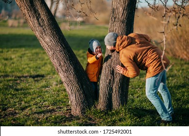 Father And Daughter Playing In Park On Green Grass. Father's Day. Little Girl Plays With Dad Outside. Father Plays Hide And Seek With Daughter In Park.