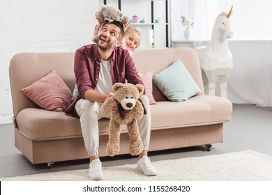 father and daughter playing with teddy bears on couch - Powered by Shutterstock