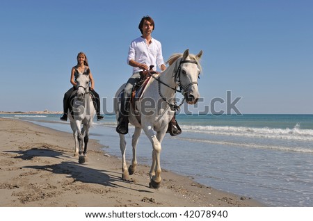 father and daughter are riding with their white horses on the beach