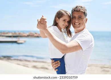 Father and daughter smiling confident dancing at seaside - Powered by Shutterstock